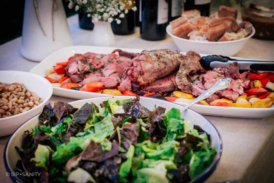 a salad, lamb dish and bread on a table