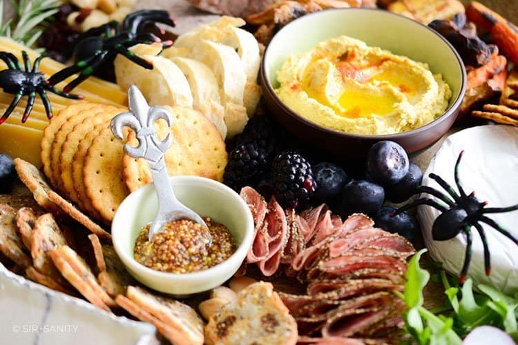 bowls of mustard and hummus with salami and crackers