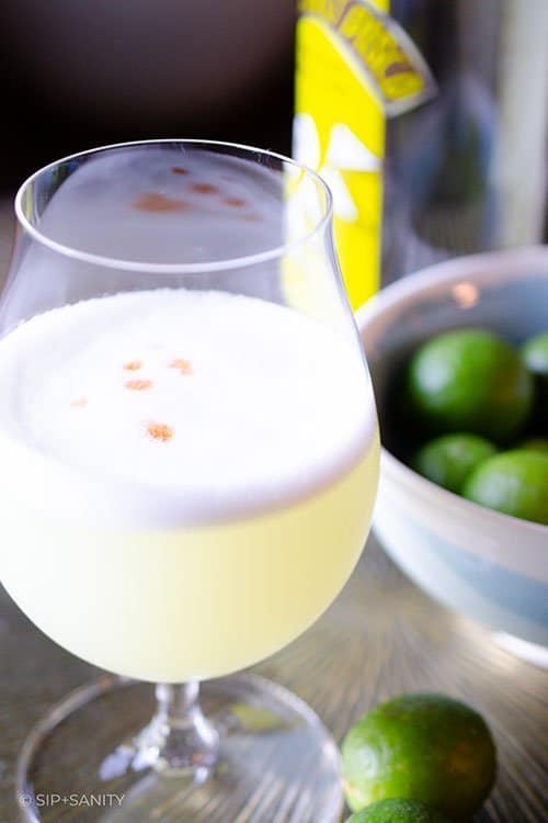 pisco sour next to a bowl of limes