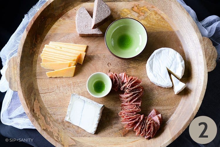 wood board with bowls, cheese and salami