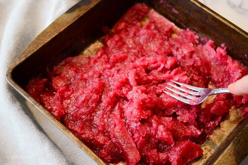 cranberry-lime granita in a pan being mixed with a fork