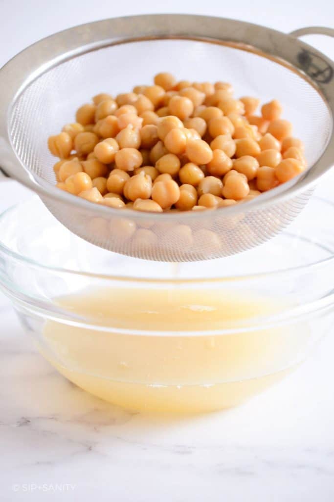 chickpeas in a strainer and aquafaba in a bowl