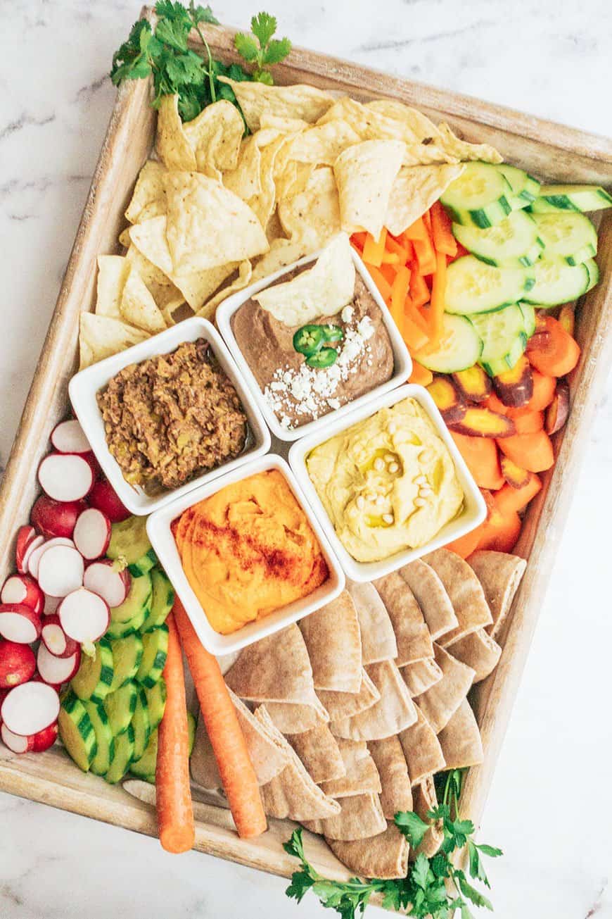 a snack board with easy homemade hummus, raw veggies, chips and pita bread