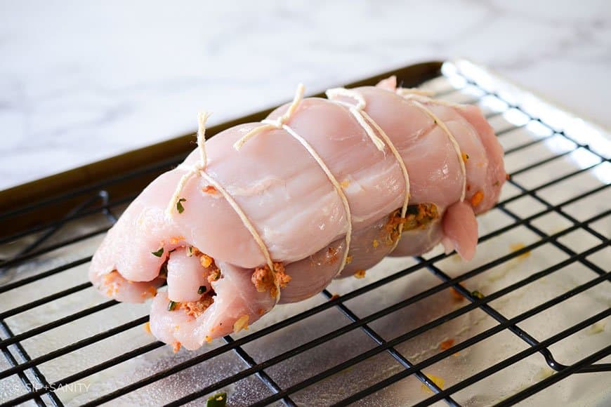 trussed and stuffed turkey breast on a sheet pan