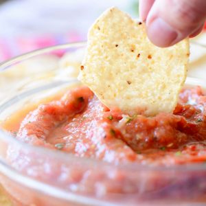 dipping a chip into charred tomato salsa