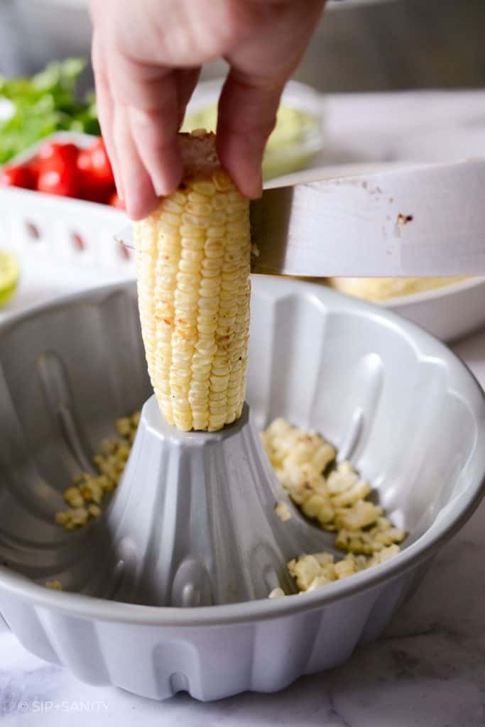 cutting corn off the cob on top of a bundt pan