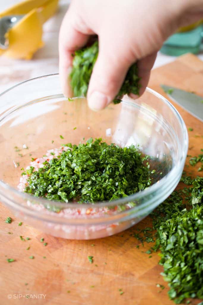 a hand adding herbs to a bowl