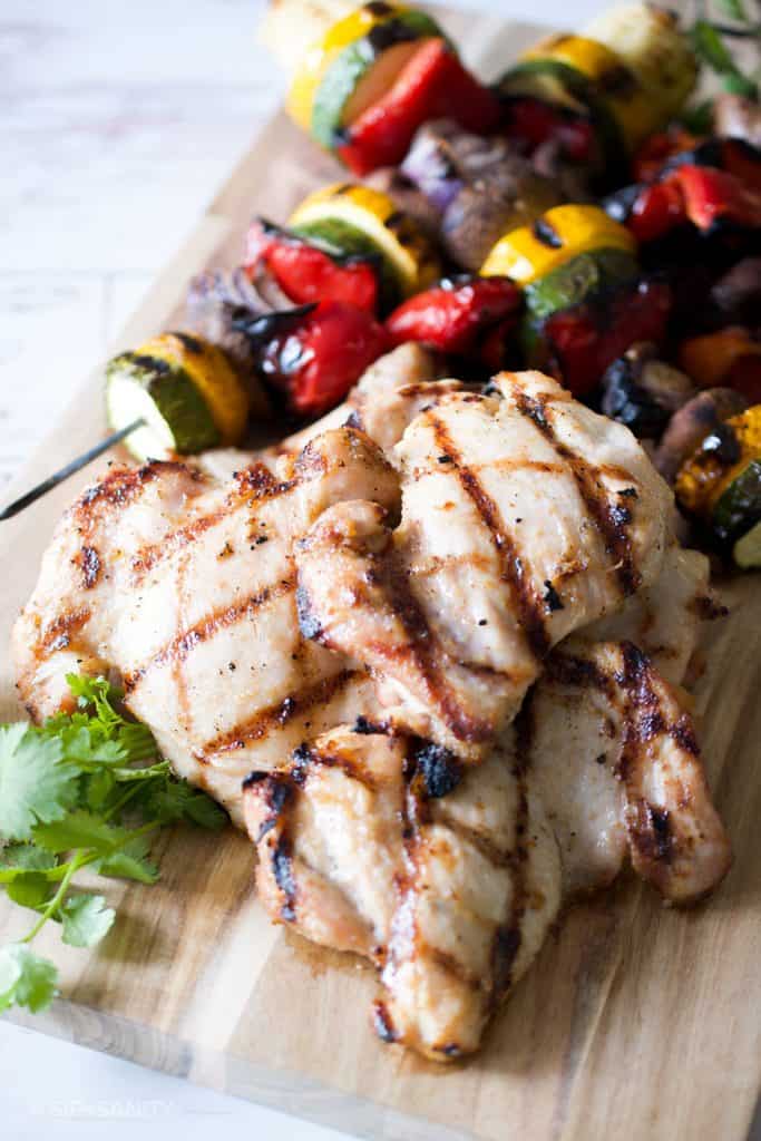 grilled chicken on cutting board with vegetable skewers