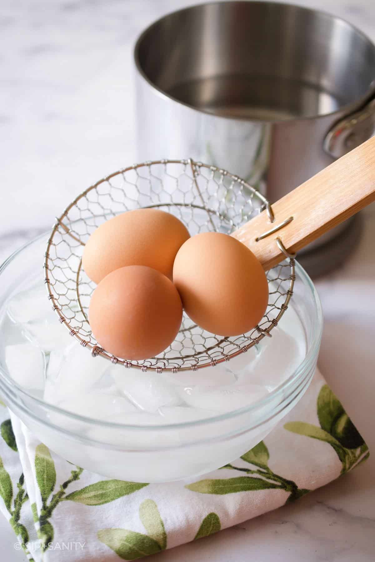 boiled eggs going into a bowl of ice water