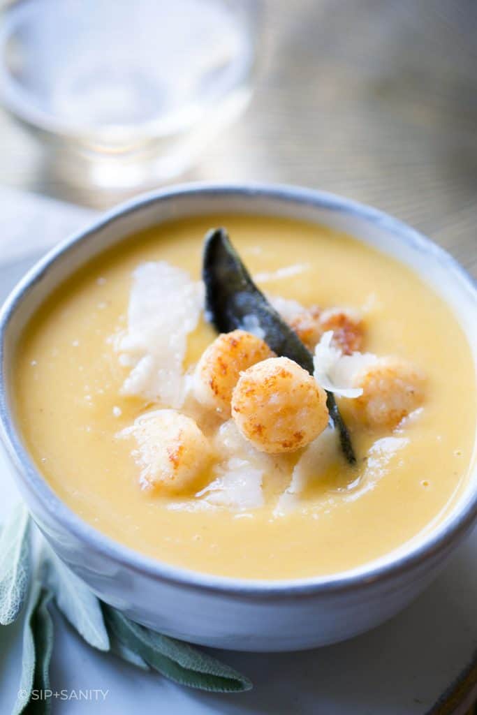 bowl of soup next to glass of white wine
