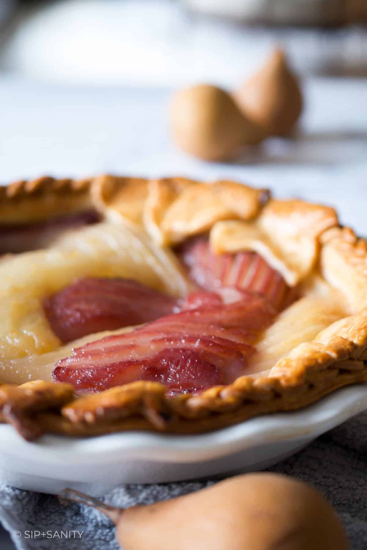 wine poached pear pie with fresh pears in background