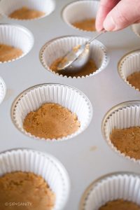 pressing cookie crumbs into muffin cups