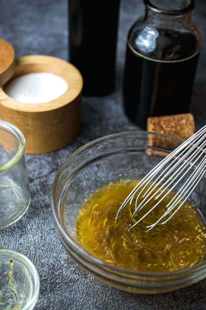 whisking maple mustard dressing in a bowl