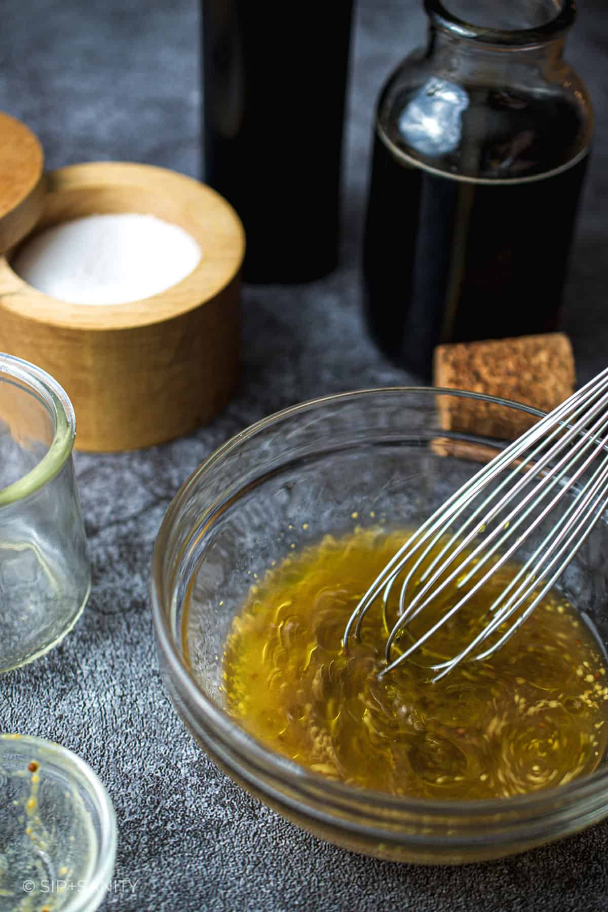 whisking maple mustard dressing in a bowl