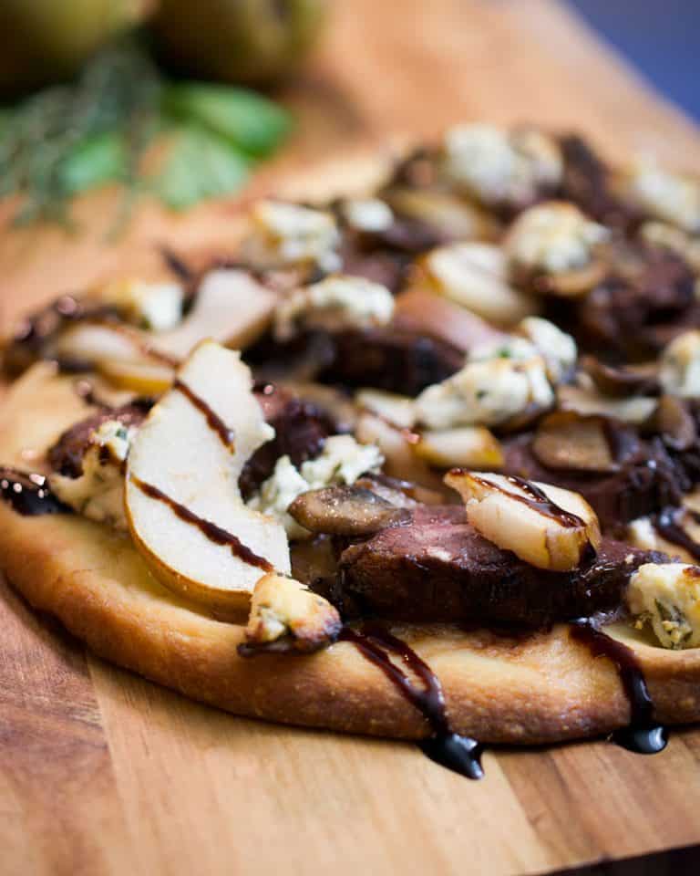 duck and mushroom pizza on a board