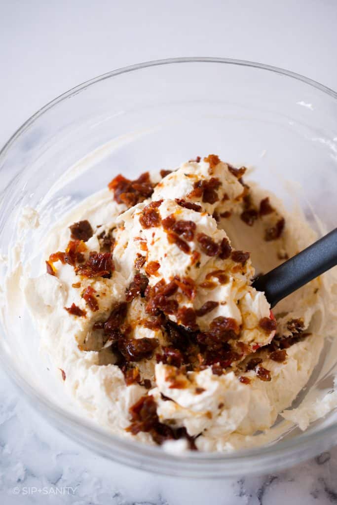 mixing sundried tomato goat cheese spread