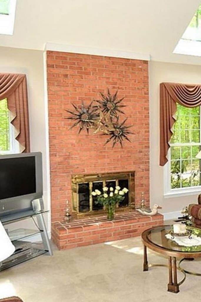 A fireplace with light orange brick and brass accents.