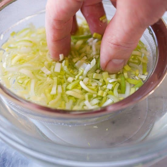 Washing sliced leeks in a bowl of water.