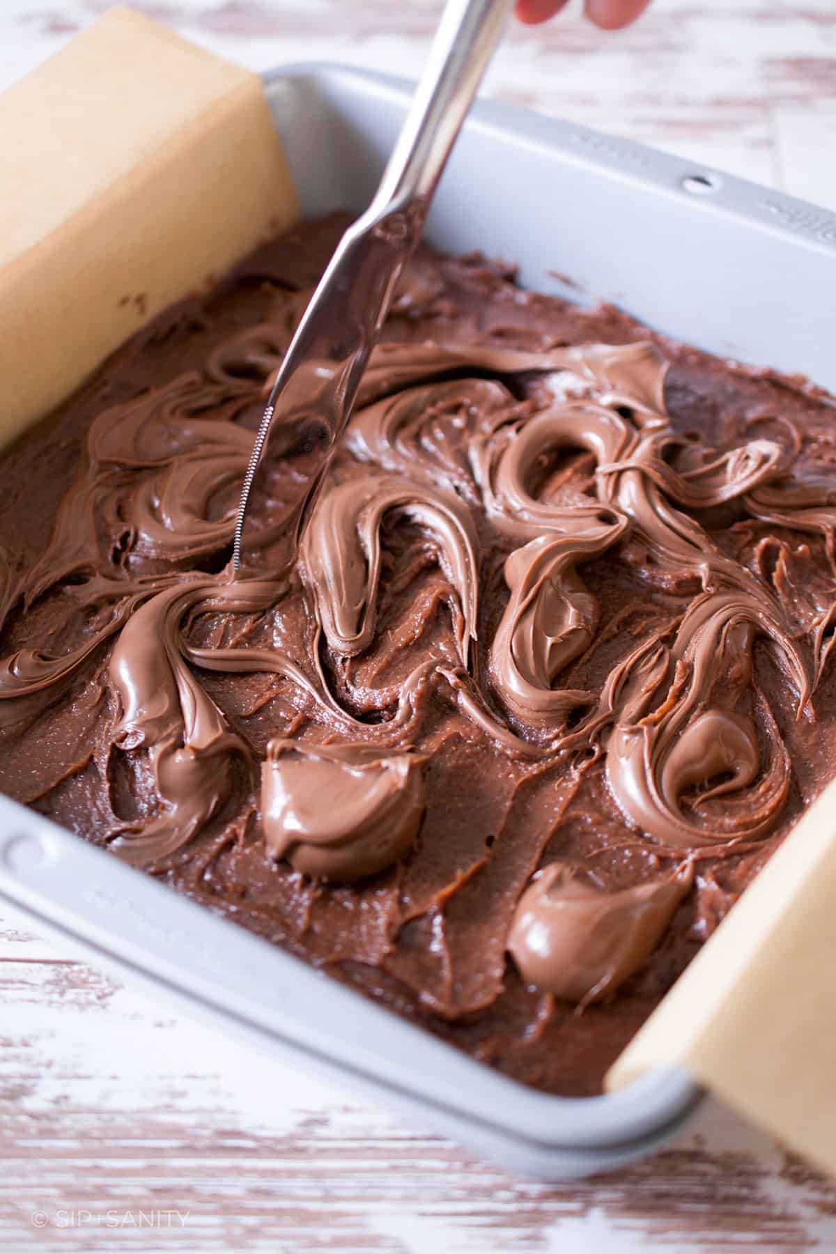 Swirling hazelnut cocoa spread on top of brownie batter.