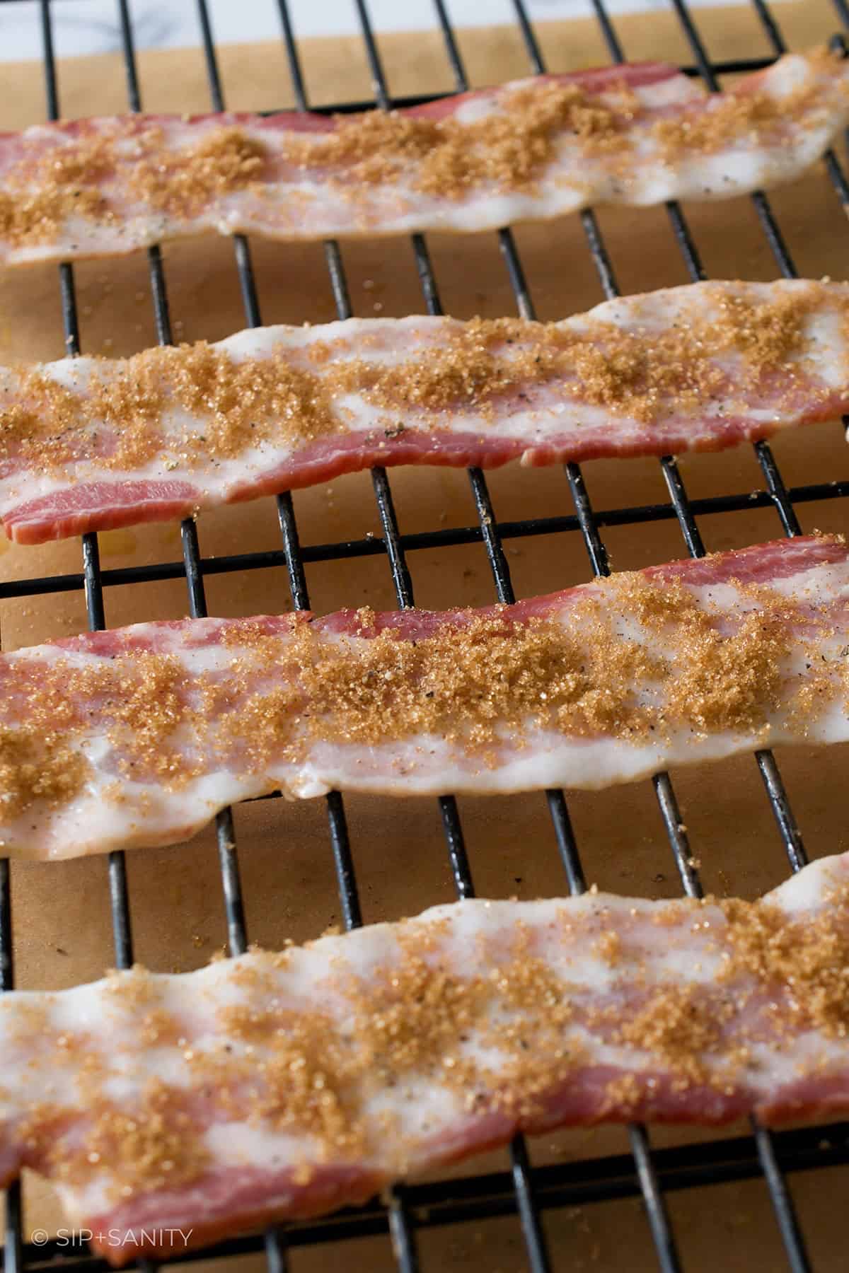 Slices of brown sugared bacon on a wire rack.
