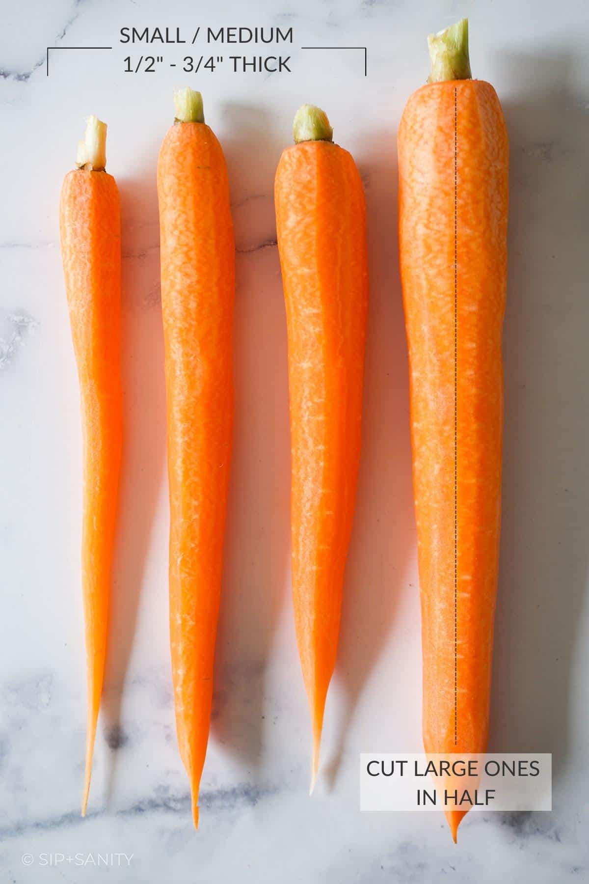 Four carrots of different sizes on a white surface.