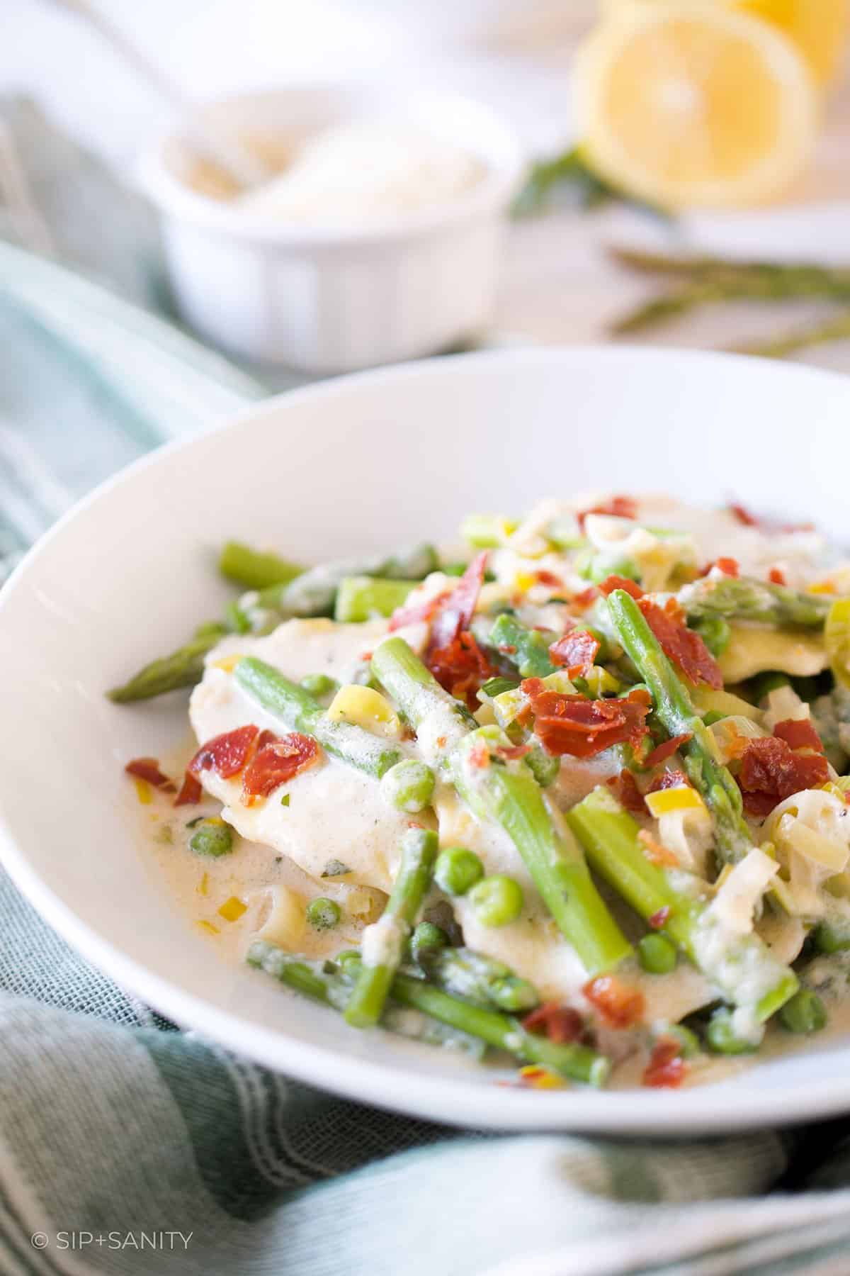 Creamy mushroom ravioli with spring vegetables in a bowl.