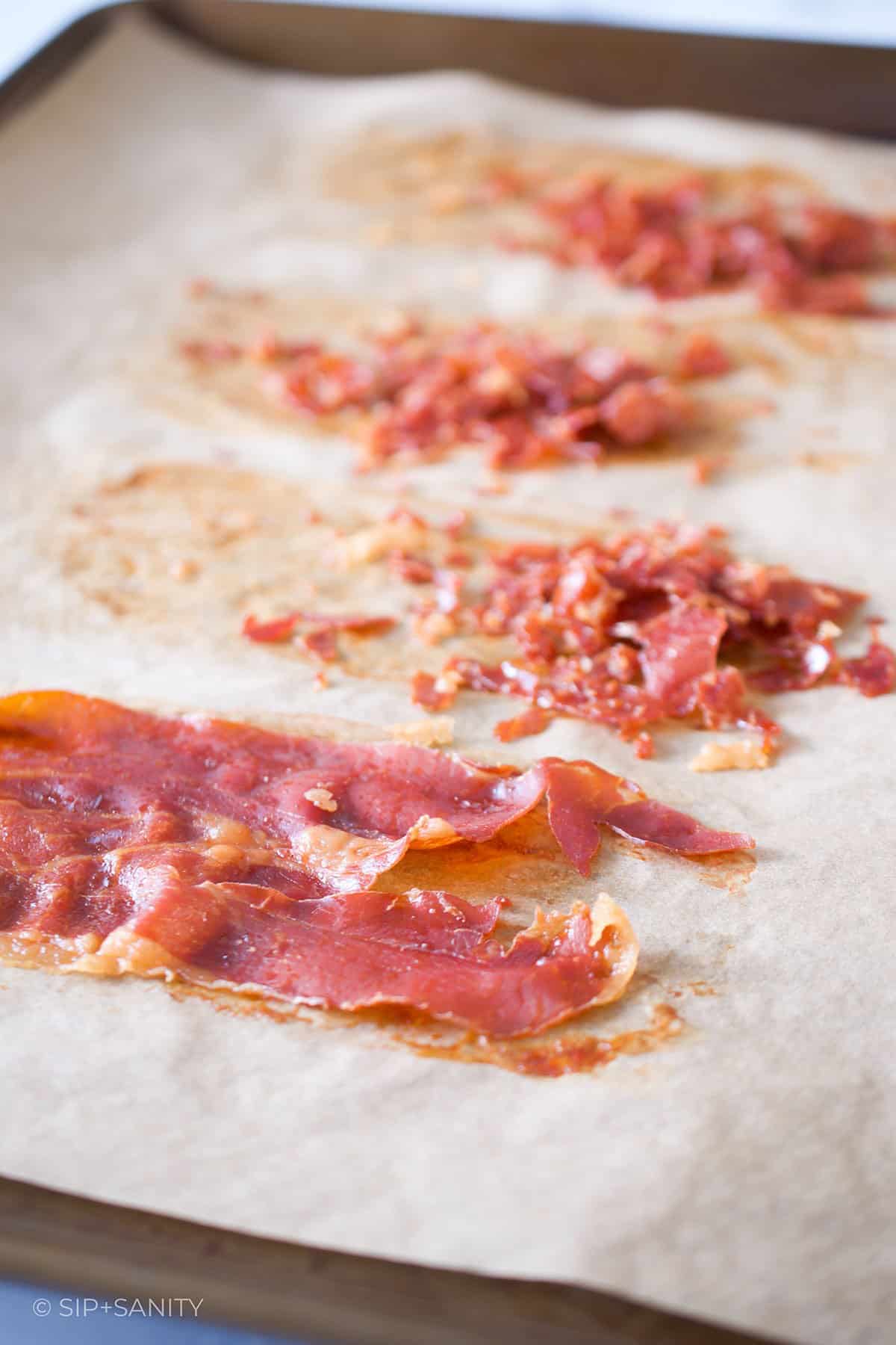Crispy prosciutto on a parchment lined sheet pan.