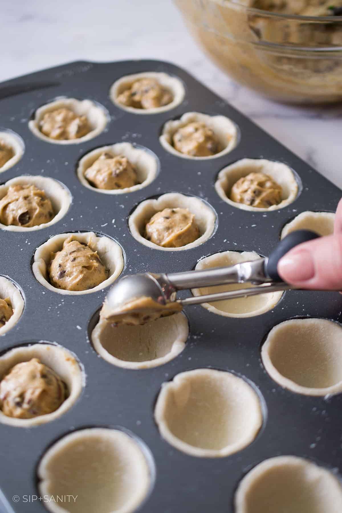 Scooping derby pie filing into the mini muffin tin.