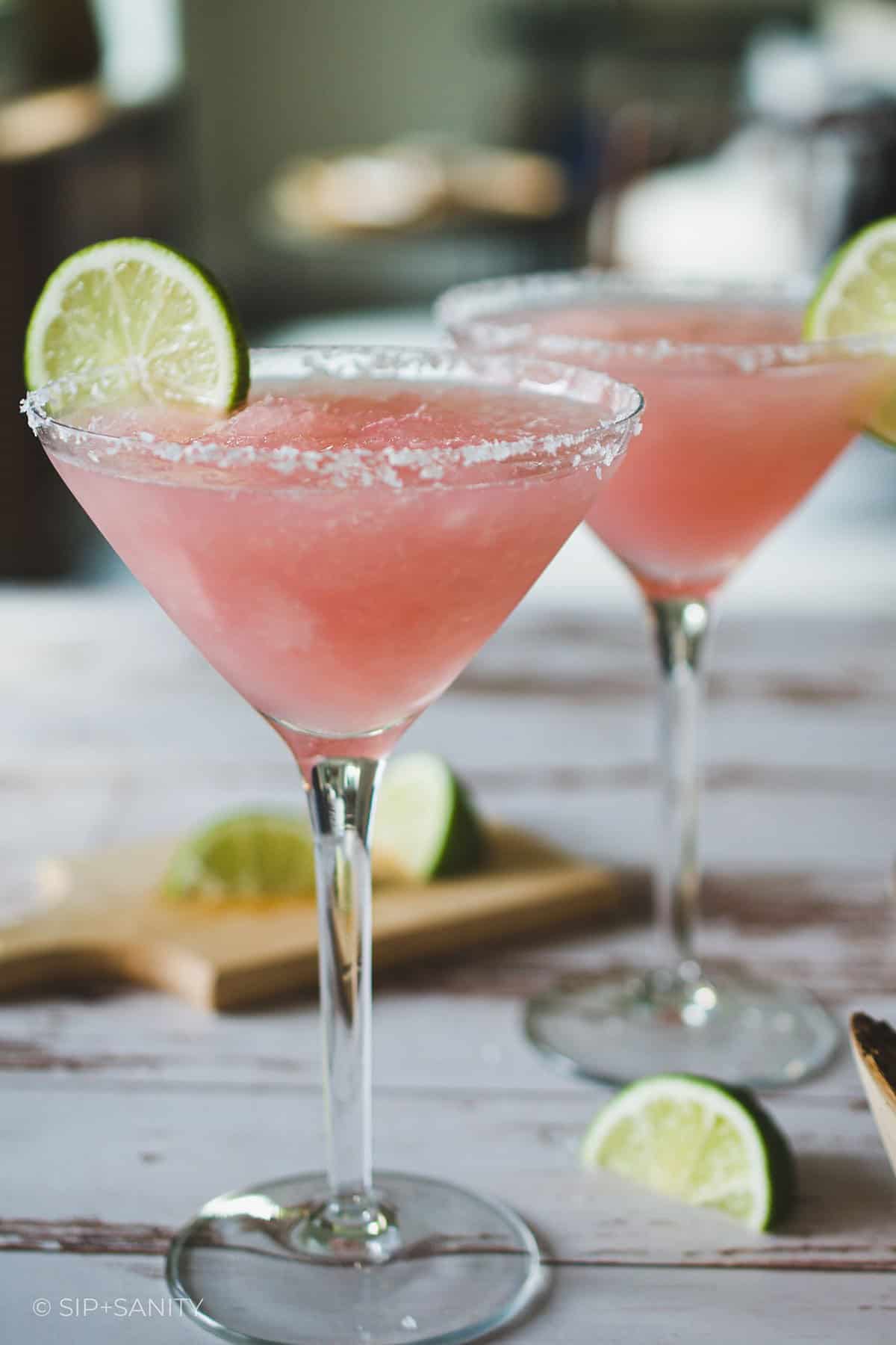 Two martini glasses filled with frozen pink cadillac margaritas.