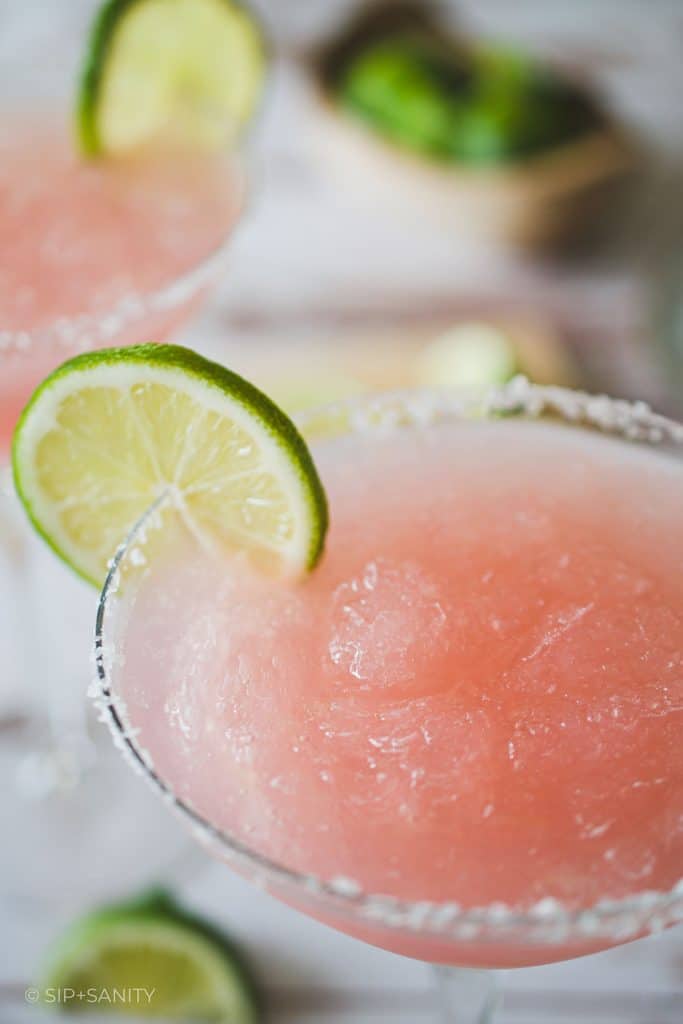 Frozen pink cadillac margarita in a glass with a salted rim.