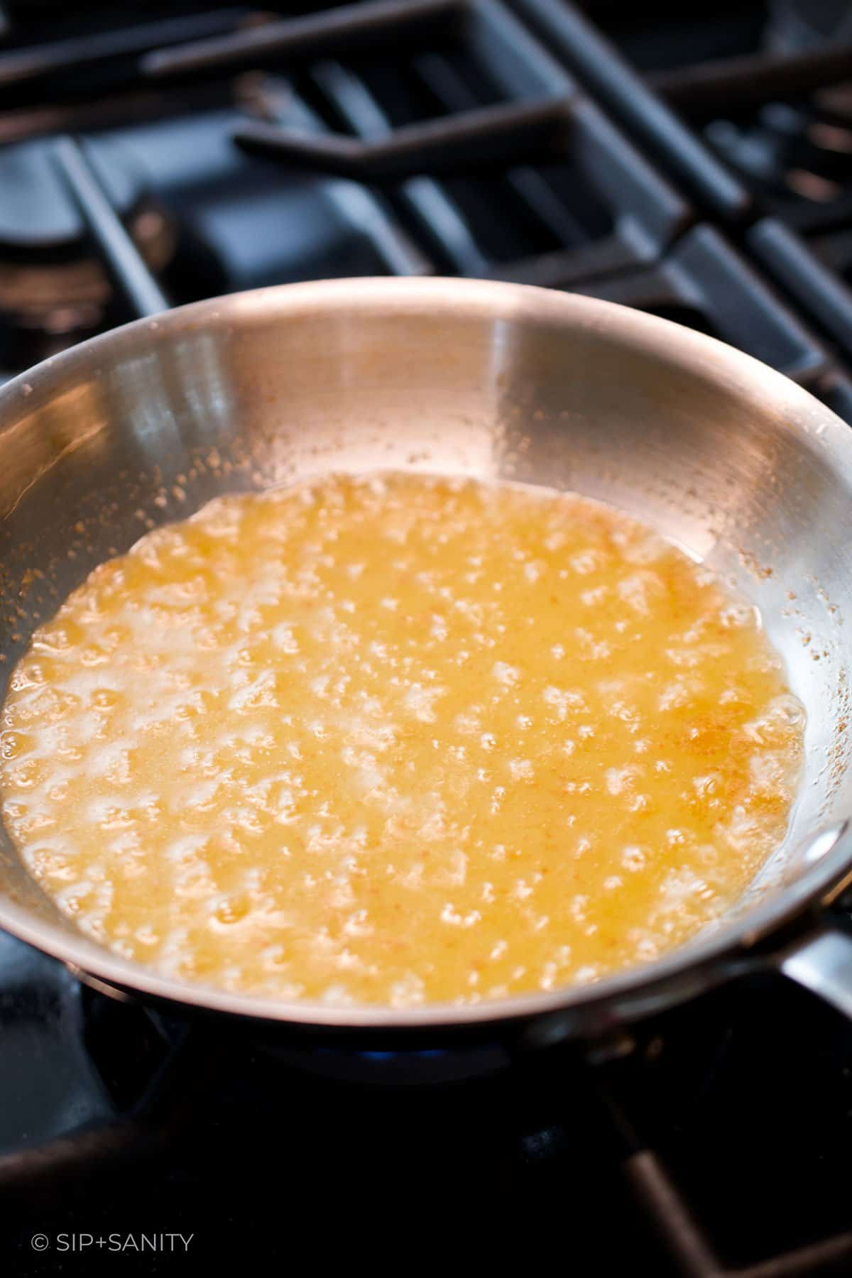 Golden milk solids in browning butter in a skillet.