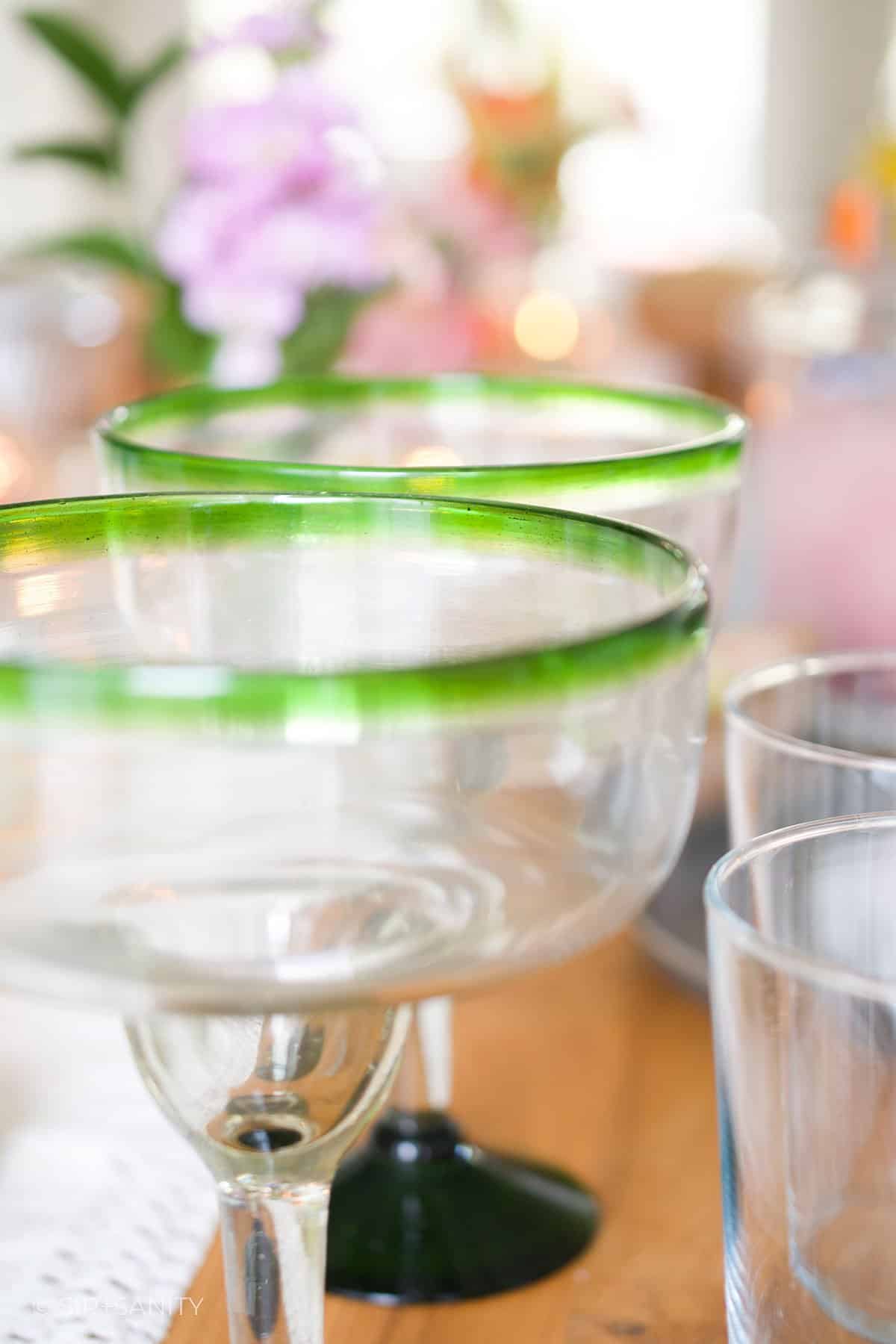 A closeup of green-rimmed margarita glasses.