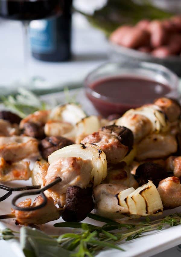 Skewers of chicken, onion and mushroom on a white platter.