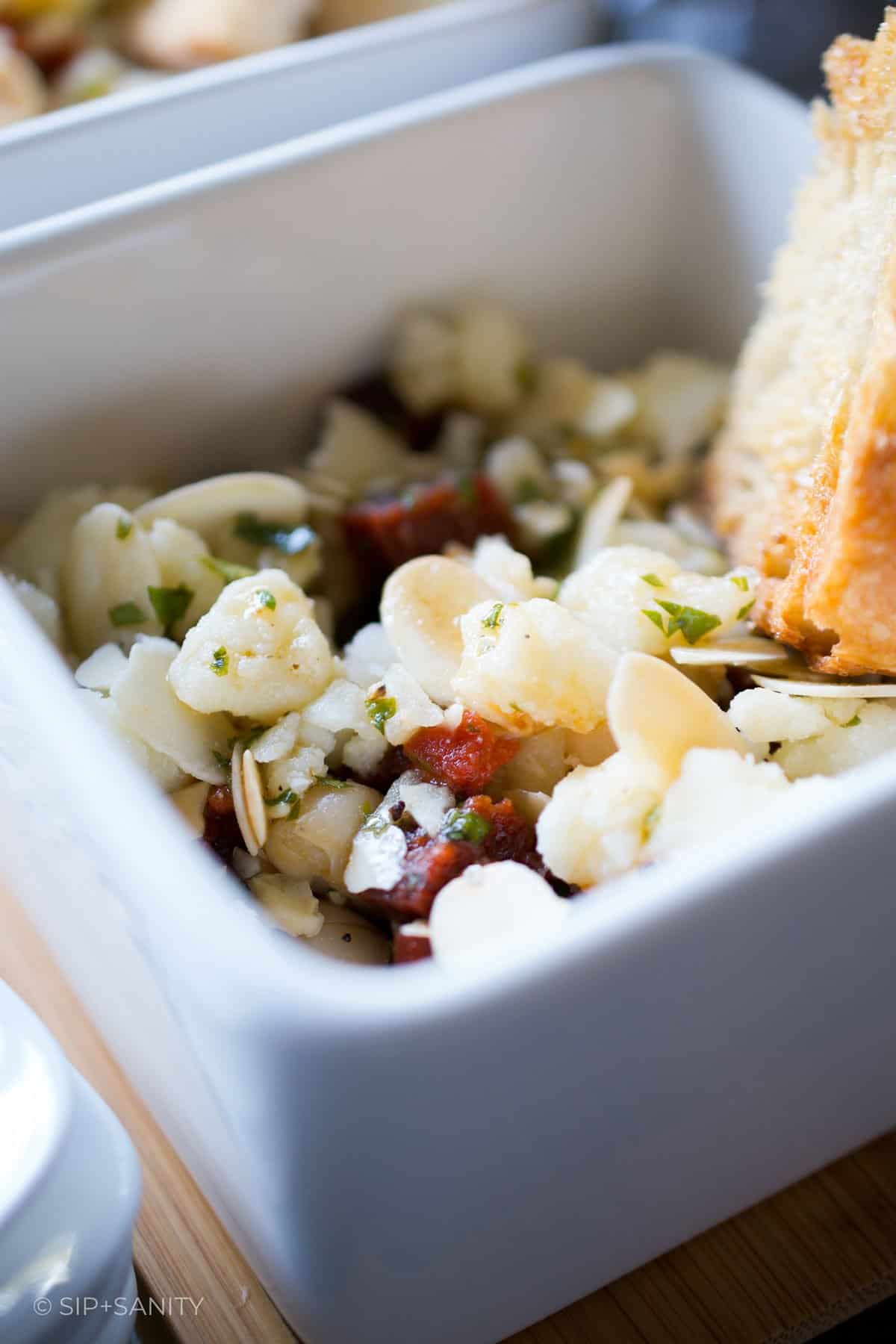 Easy tapas white bean salad in a bowl with a slice of toasted bread.
