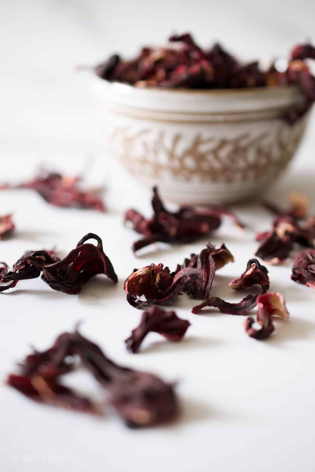 Dried hibiscus petals scattered on a white table.
