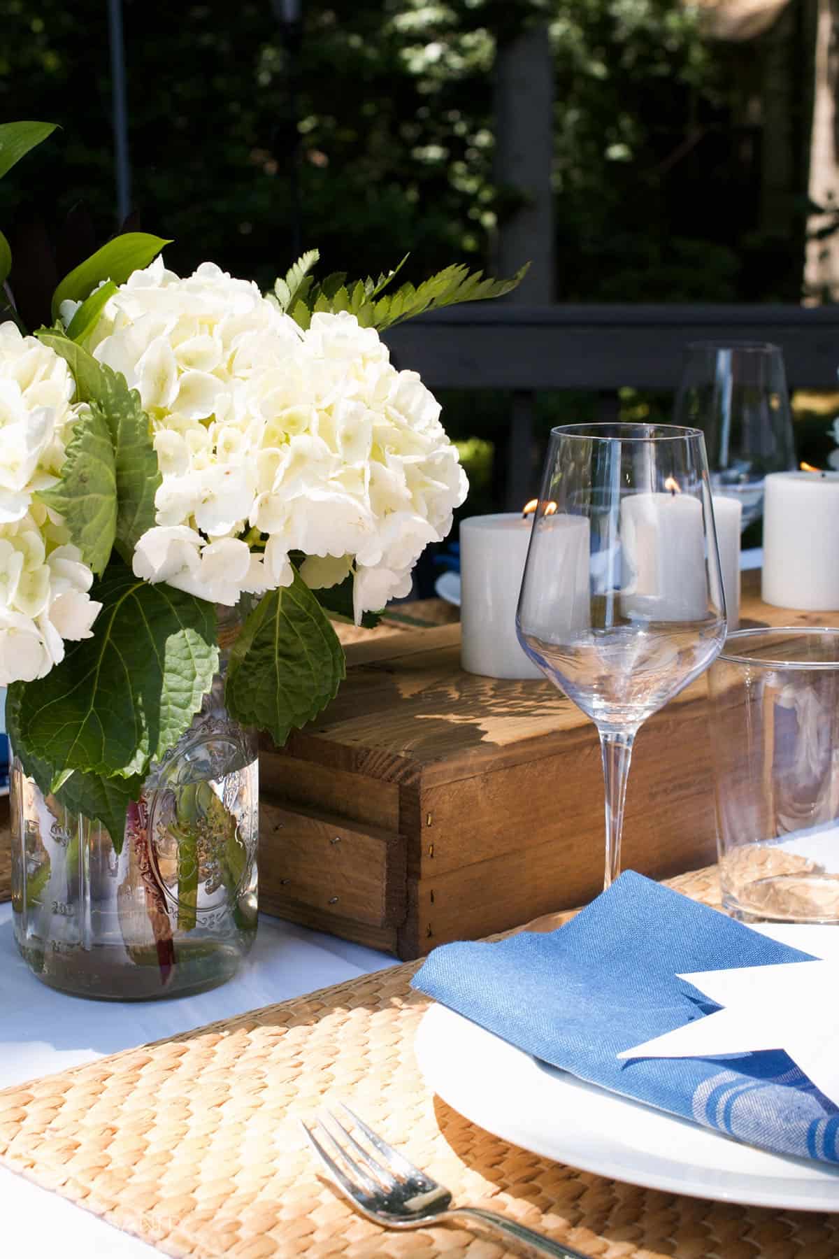 A sunny picnic table with candles and flowers.