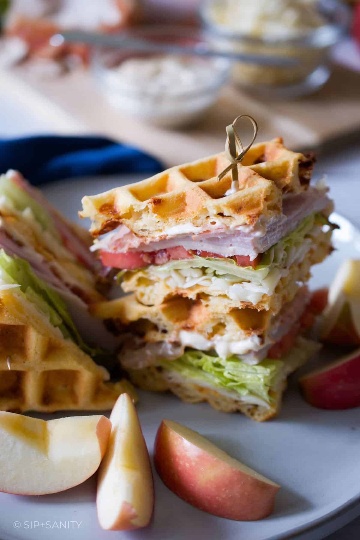 Waffle club sandwiches on a plate with apple slices.