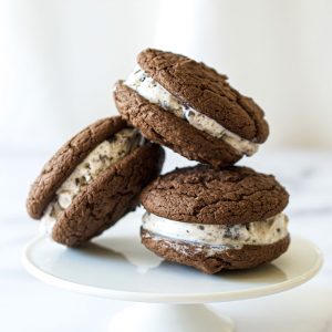 Three cookie ice cream sandwiches on a white plate.