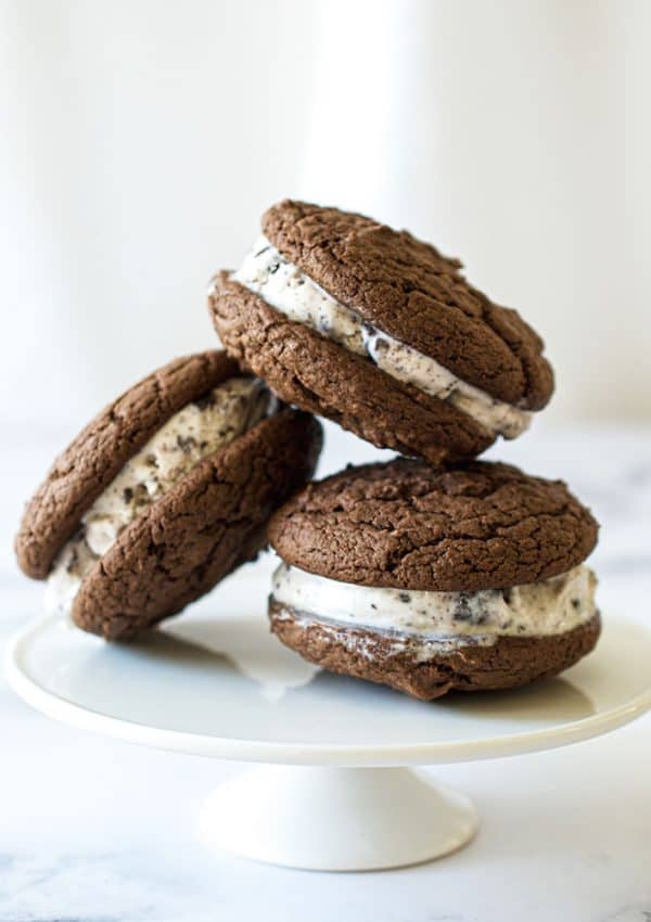 Three cookie ice cream sandwiches on a white plate.