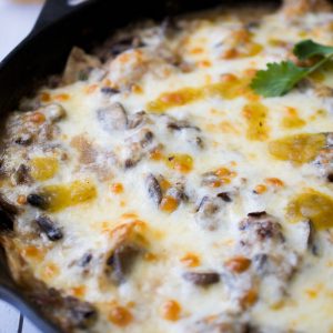Cast iron skillet filled with a cheesy topped casserole.