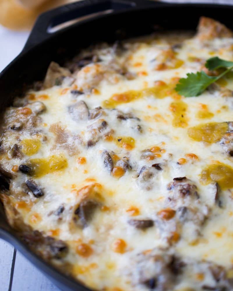 Cast iron skillet casserole topped with melted cheese and salsa verde.