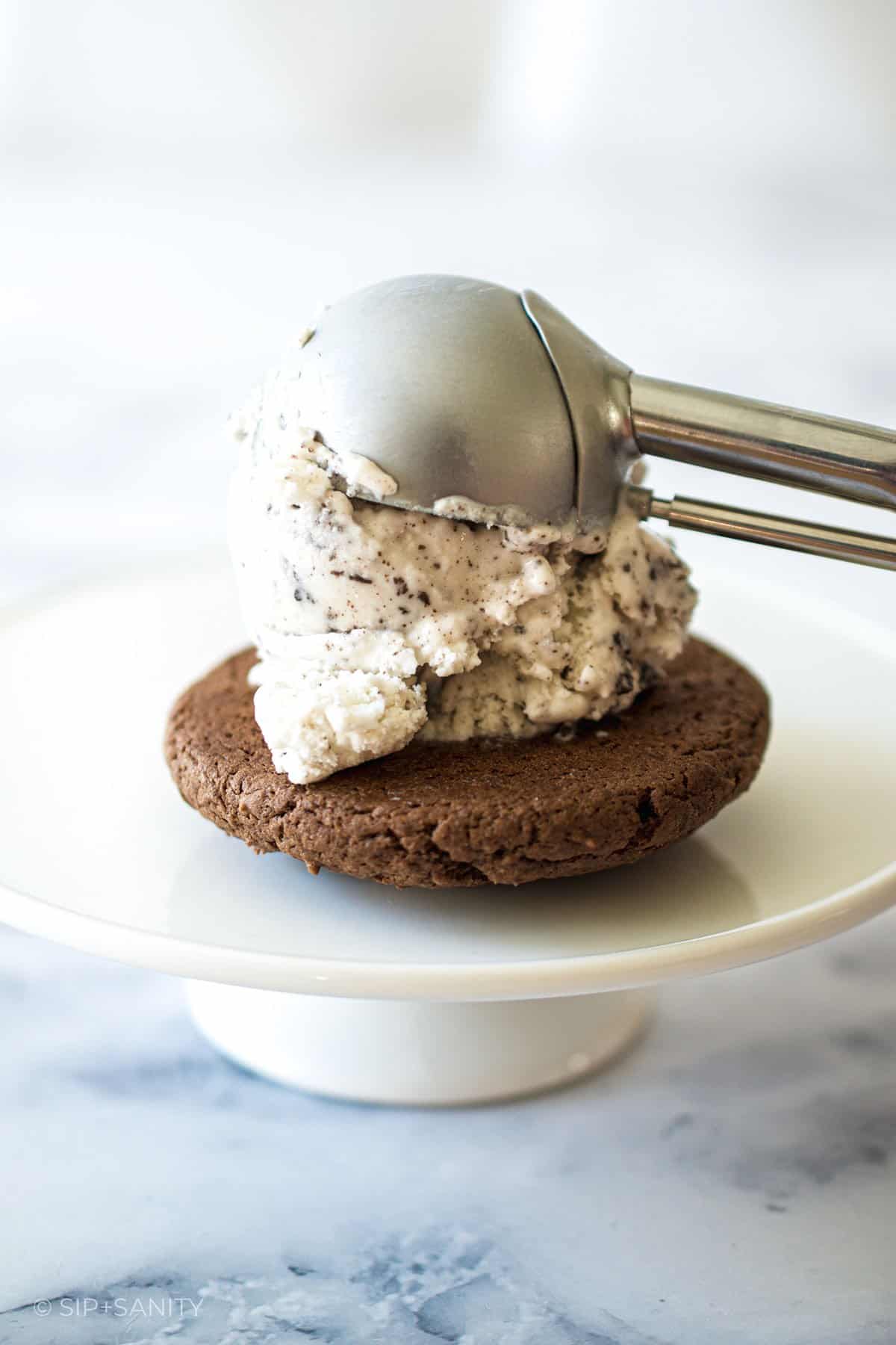 Scooping ice cream onto a chocolate cookie.