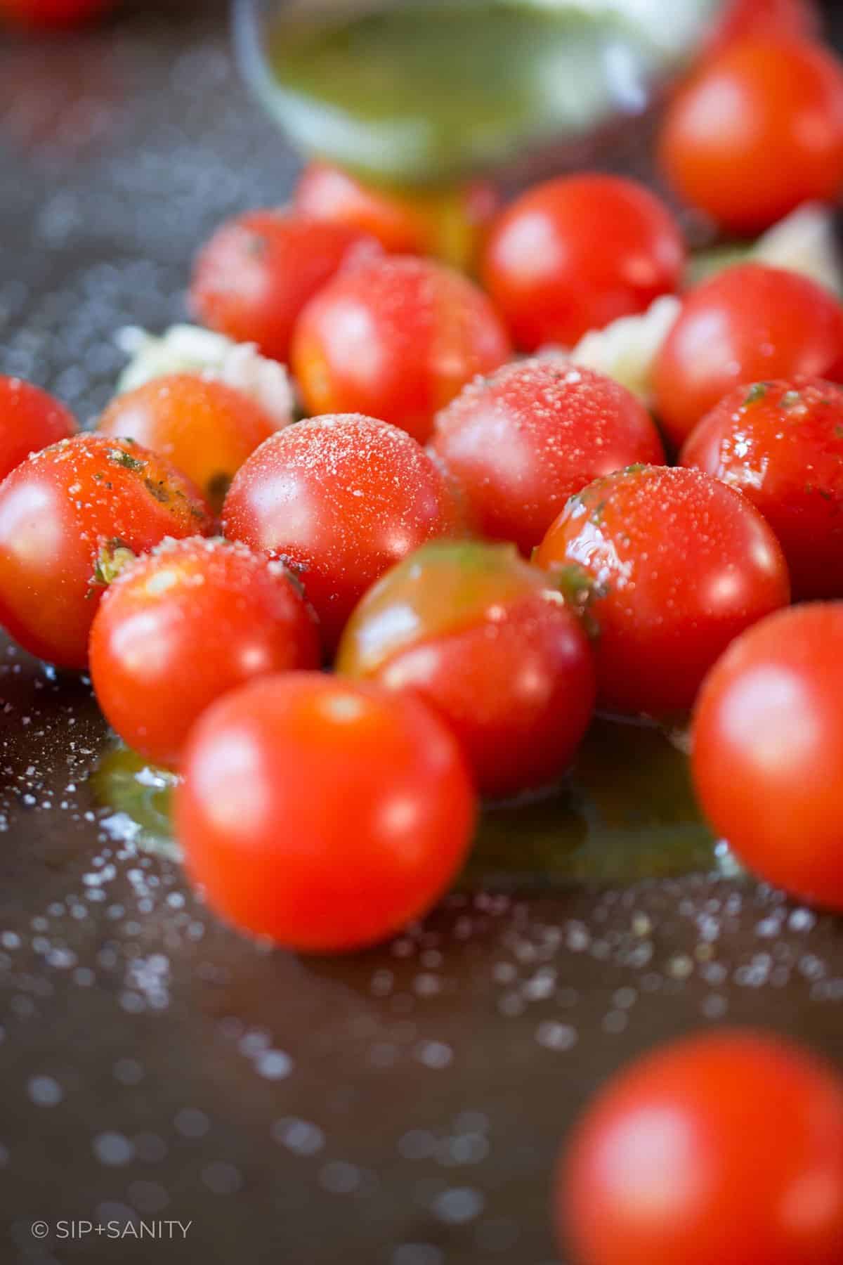 Raw tomatoes on a sheet pan with garlic and basil oil.