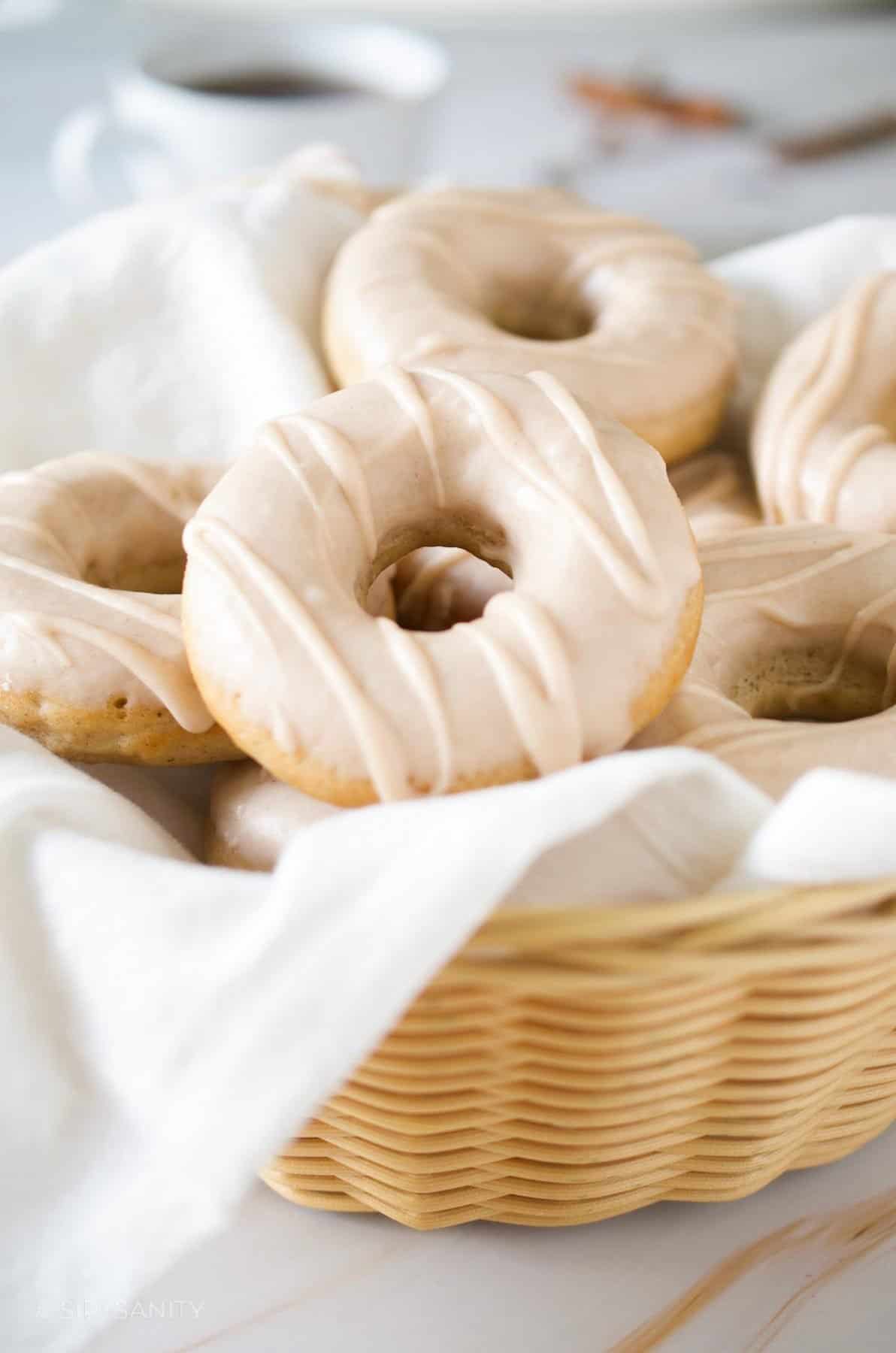 A basket filled with iced donuts.