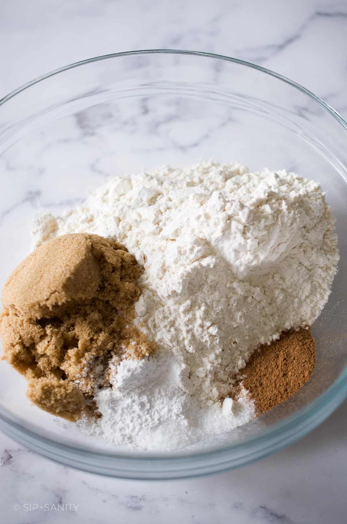 Flour, spices and brown sugar in a glass bowl.