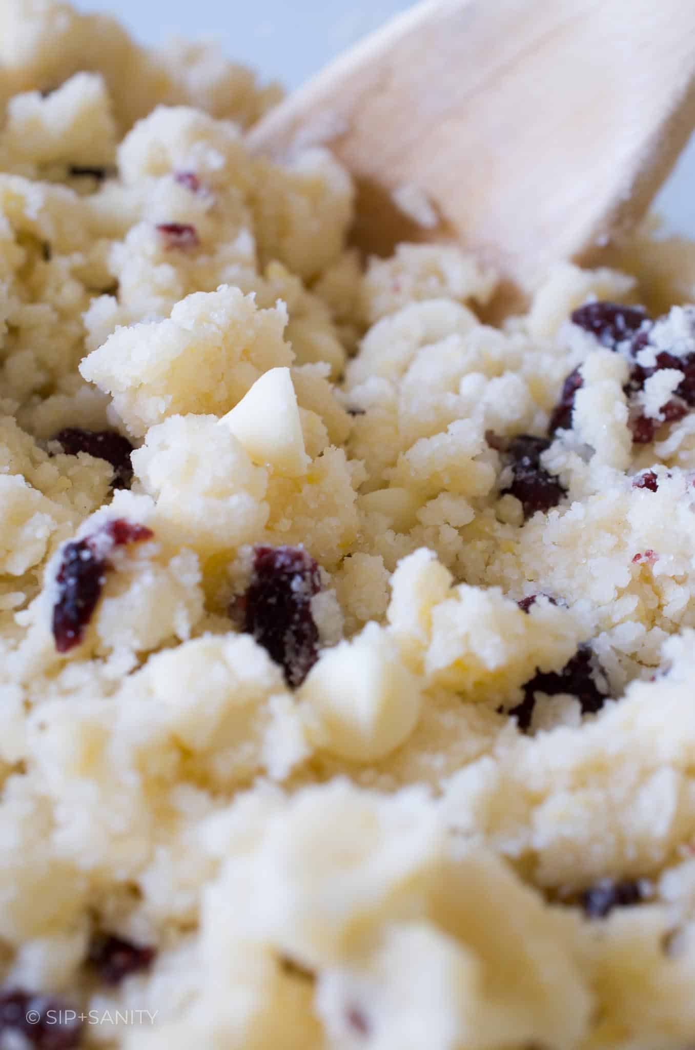 Sugar cookie dough with white chocolate chips and cranberry pieces mixed in.