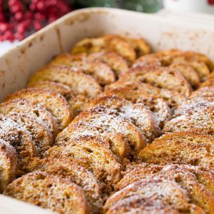A casserole filled with baked gingerbread eggnog french toast dusted with powdered sugar.