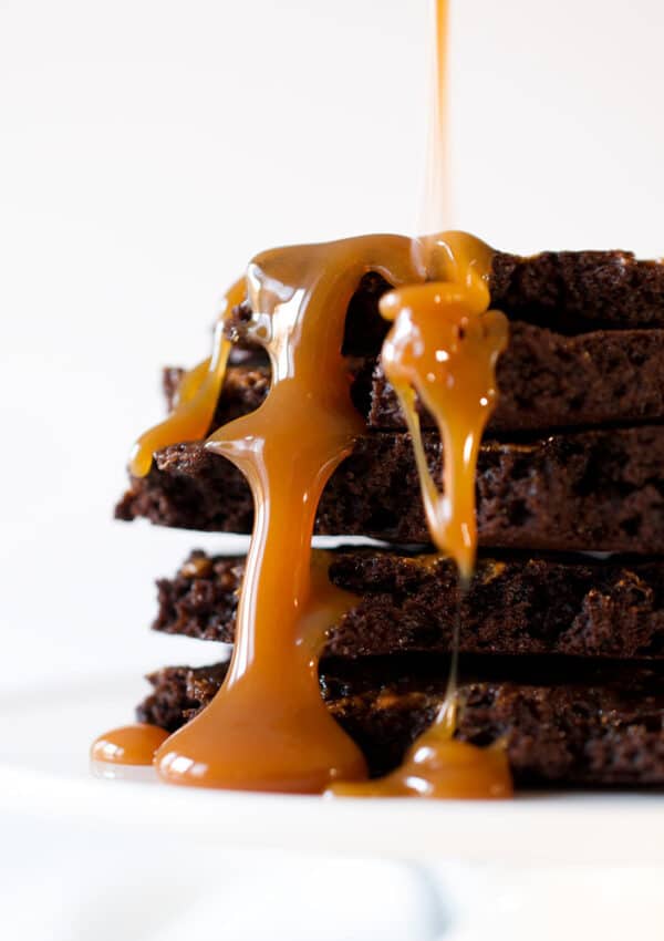 A stack of brownie brittle pieces with caramel sauce dripping down.