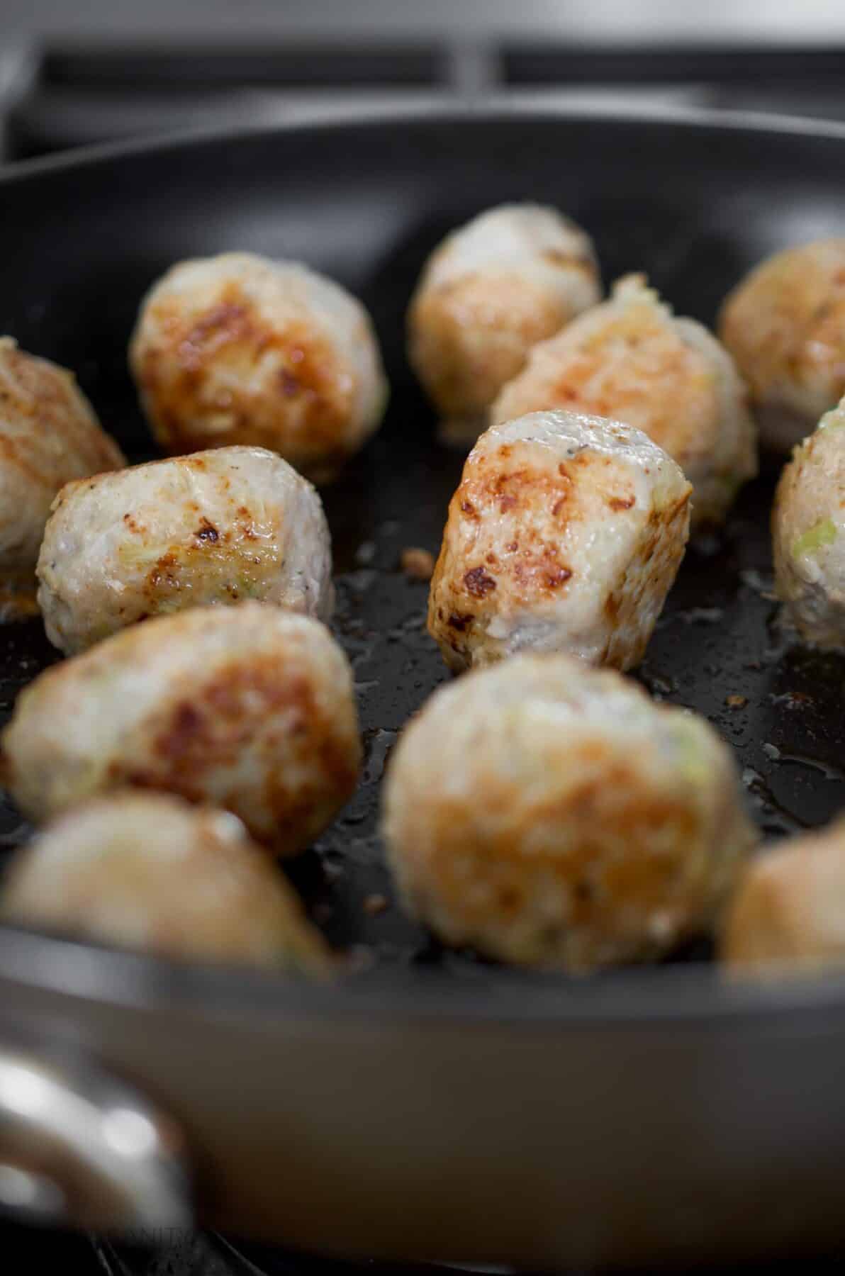 Chicken meatballs being browned in a skillet.