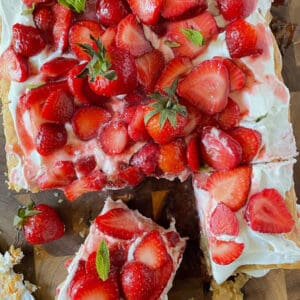 A giant strawberry shortcake dessert made with puff pastry on a cutting board.